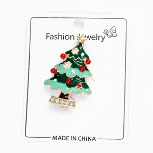 Détail d'une broche sapin de Noël en émail vert avec perles rouges et strass blancs