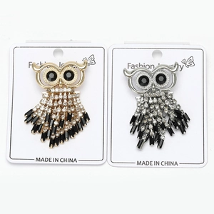 Close-up of owl pins with black and white crystals in gold and silver finishes