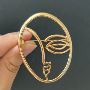 Macro shot of gold abstract face brooch with polished finish and artistic lines