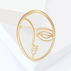 Abstract golden face brooch with minimalist artistic lines and polished metallic finish