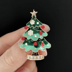 Gros plan sur la broche sapin de Noël en émail vert avec dorure et strass brillants
