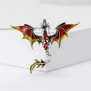 Detail of red and yellow enamel dragon brooch with silver metal and gemstone wings