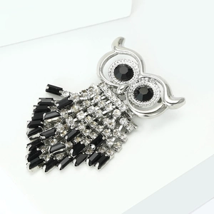 Macro detail of silver owl brooch featuring white rhinestones and black gem eyes