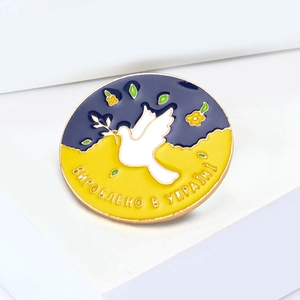 Vintage dove of peace enamel brooch with olive branch on a blue and yellow background
