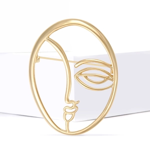 Artistic golden abstract face brooch with elegant metal wire frame and oval design