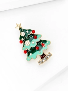 Détail d'une broche sapin de Noël avec émail vert, cloches rouges et strass brillants