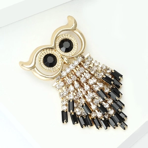 Macro detail of golden owl brooch with sparkling rhinestones and black tassel charms