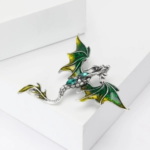 Detailed view of enamel dragon brooch with green gemstones and silver metal scales