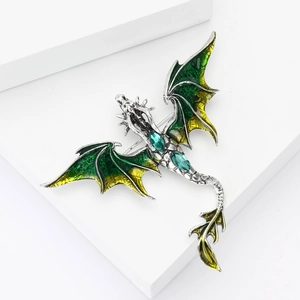 Macro detail of silver dragon brooch with green enamel wings and marquise rhinestones