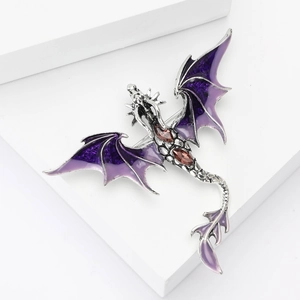 Detail of purple enamel dragon brooch with silver finish and red gemstone accents