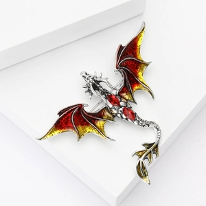 Close-up of dragon brooch with red yellow enamel wings and inlaid red gemstones