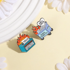 Detail of creative enamel pins featuring flaming trash bins with humorous text designs
