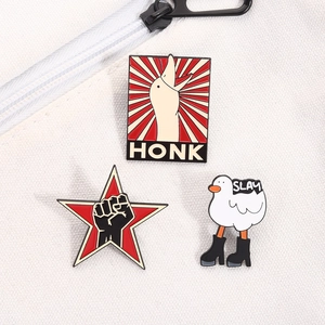 Detailed close-up of Honk goose, Slay boot goose, and star fist enamel lapel pins