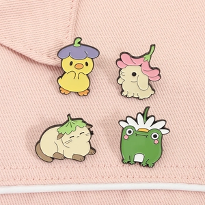 Detail of four cute animal enamel pins including a cat, rabbit, frog, and duck on pink fabric