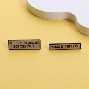 Close-up of rectangle enamel pins with Music is Medicine for the Soul text design