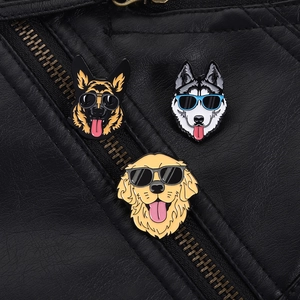 Trois pin's chiens en émail avec lunettes sur une veste en cuir noir détail