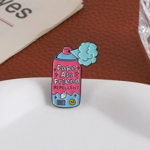 Détail du pin's émaillé rose en forme de spray avec slogan sur une assiette blanche