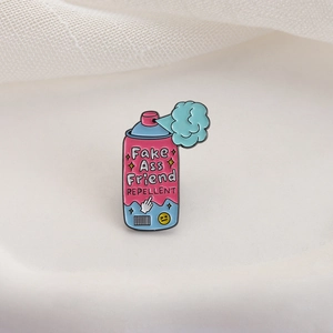 Pin's en émail rose en forme de spray avec texte humoristique sur fond de tissu
