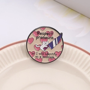 Round cat enamel pin with Respect Pronouns text and heart patterns on white plate