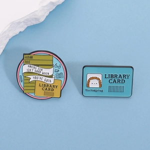 Detailed macro view of library themed enamel pins with books and hedgehog illustration