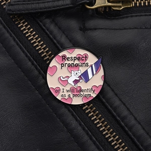 Detail of cat enamel pin with Respect Pronouns slogan on black leather jacket