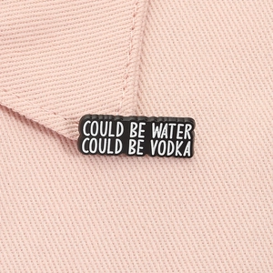 Close-up of Could Be Water Could Be Vodka enamel pin on pink fabric lapel