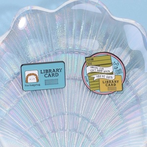 Library themed hedgehog enamel pins set on a decorative glass shell tray
