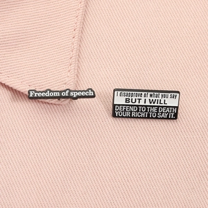 Detailed macro view of black and white enamel pins on pink fabric texture