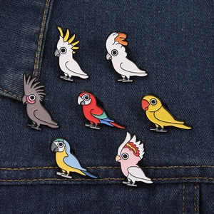 Set van zeven kleurrijke emaille papegaaienpins op donkerblauwe denim stof