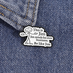 Close-up of minimalist enamel stick figure lapel pin on blue denim fabric texture