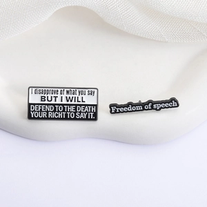 Minimalist black and white enamel pins with Freedom of Speech quotes on white tray