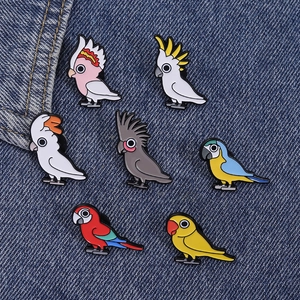 Detailopname van zeven kleurrijke emaille papegaai speldjes op een blauwe denim achtergrond
