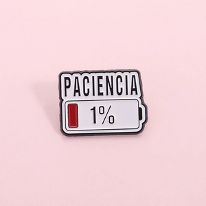 Dettaglio della spilla Paciencia in smalto con design batteria 1% su sfondo rosa