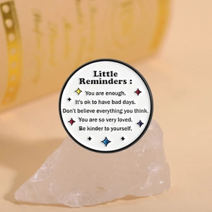 Macro shot of Little Reminders round enamel pin with inspirational quotes and stars