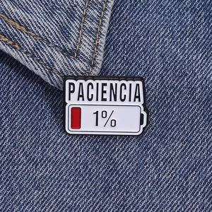 Macro della spilla smaltata Paciencia 1 percento di batteria su tessuto denim blu