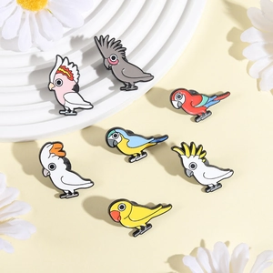 Set van zeven kleurrijke emaille speldjes met diverse cartoonpapegaaien op een plateau