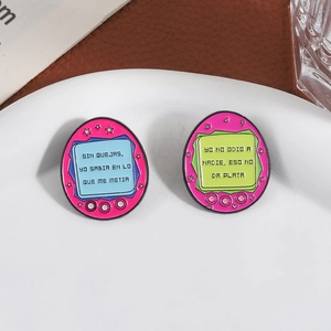 Pink electronic pet enamel pins with Spanish quotes displayed on white ceramic plate