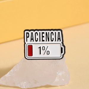 Vista dettagliata della spilla smaltata batteria 1% PACIENCIA su un cristallo bianco