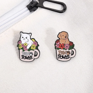 Detail of enamel pins featuring a cat and dog in pink mugs with Paw Power lettering