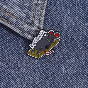 Dettaglio di una spilla smaltata con topo che si allena su tessuto denim blu scuro