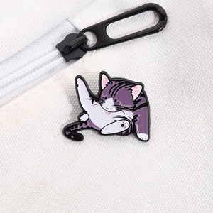 Detail showing an enamel cat pin on a canvas bag featuring a cute purple cat licking its paw