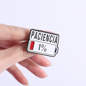 Dettaglio della spilla in smalto Paciencia 1% batteria tenuta su sfondo viola