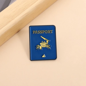 Macro detail of a blue enamel passport brooch with a golden crab design and gold metal edges