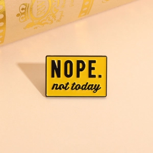 Detailed view of yellow enamel brooch featuring NOPE not today quote on metal pin