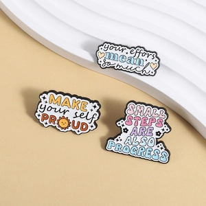 Trois pin's émaillés motivants aux couleurs pastel sur un fond crème élégant