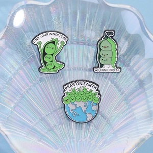 Detailed view of three creative pea enamel pins displayed on a pearl shell tray