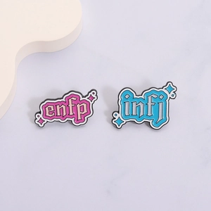 Vue macro des pin's émaillés rose ENFP et bleu INFJ avec des motifs d'étoiles mignons
