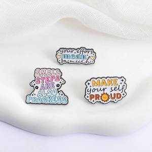 Lot de trois pin's en émail coloré avec phrases inspirantes sur un support blanc