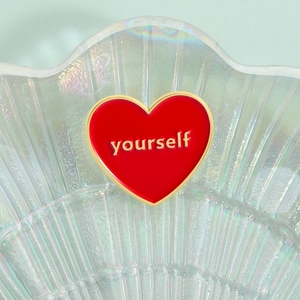 Macro de la broche coeur en émail rouge avec bordure dorée et gravure de texte