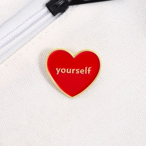 Broche cœur en émail rouge avec texte yourself doré sur un sac en toile blanc